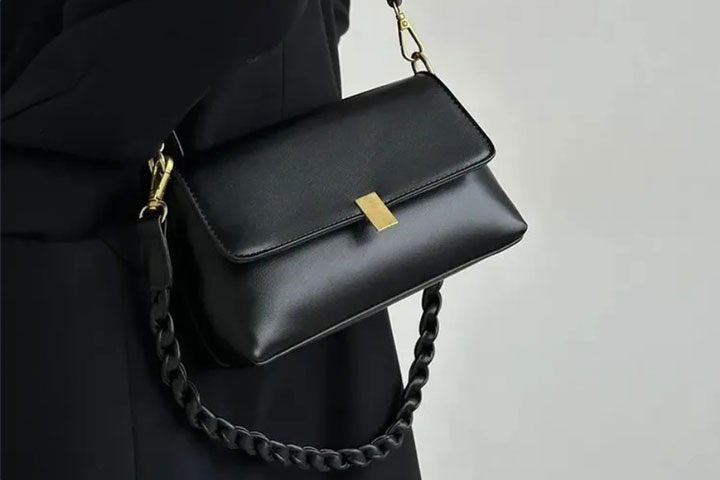 Svart axelremsväska med justerbara remmar och fack